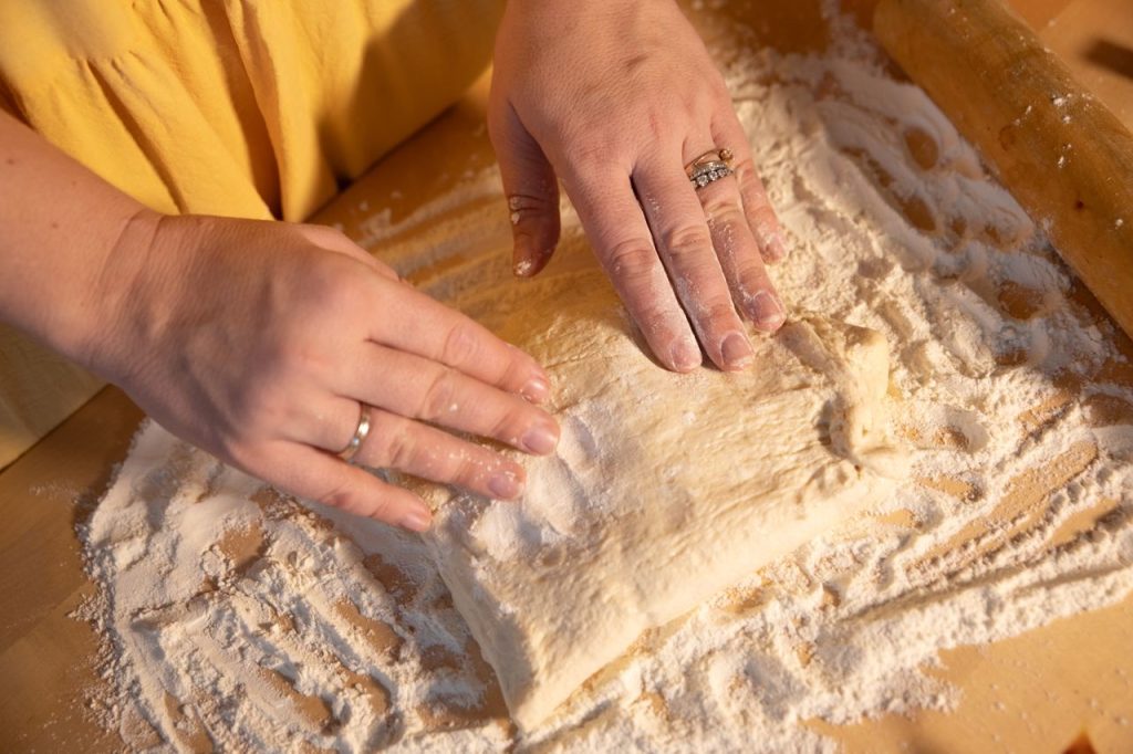 Close-up of hands kneading dough on a wooden surface with flour.